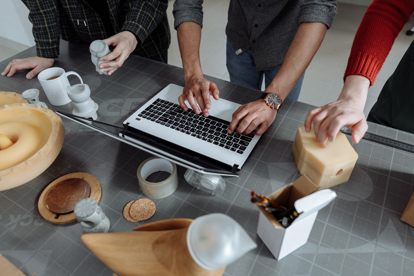 Personas colaborando en un proyecto de diseño con un computador y materiales creativos.